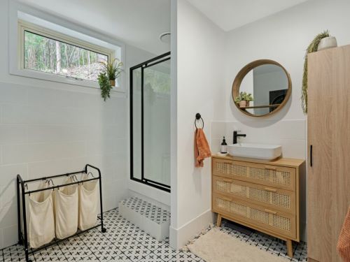 Da Vinci Vaticano Matt 200x200mm tiles laid on a bathroom floor featuring a geometric pattern complementing a rattan vanity, round mirror, and black-framed shower screen.