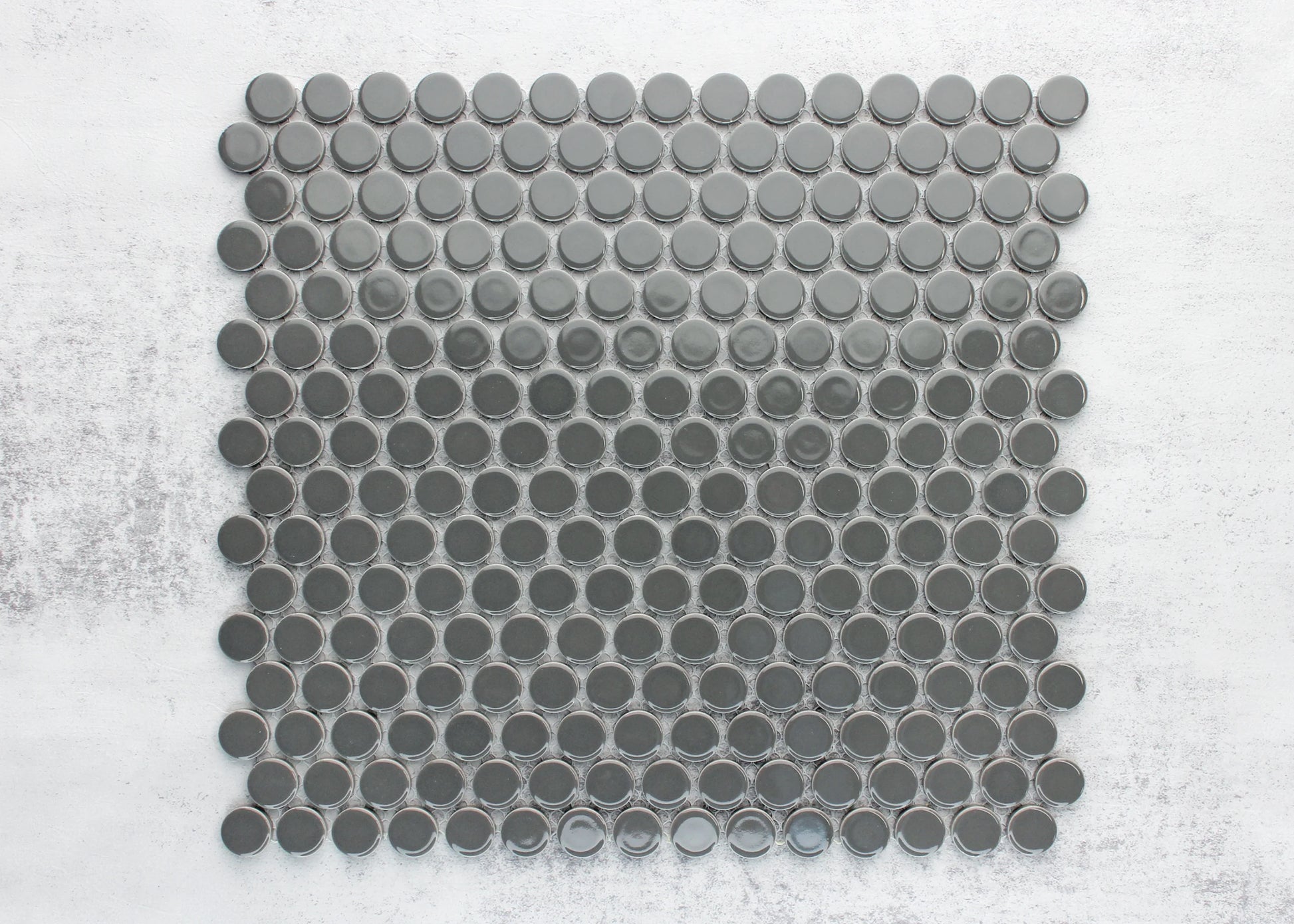 A flat lay sample sheet of Dark Grey Gloss Diameter Glazed Porcelain Penny Round 19mm tiles showing glossy circular mosaic pieces arranged in a grid pattern.