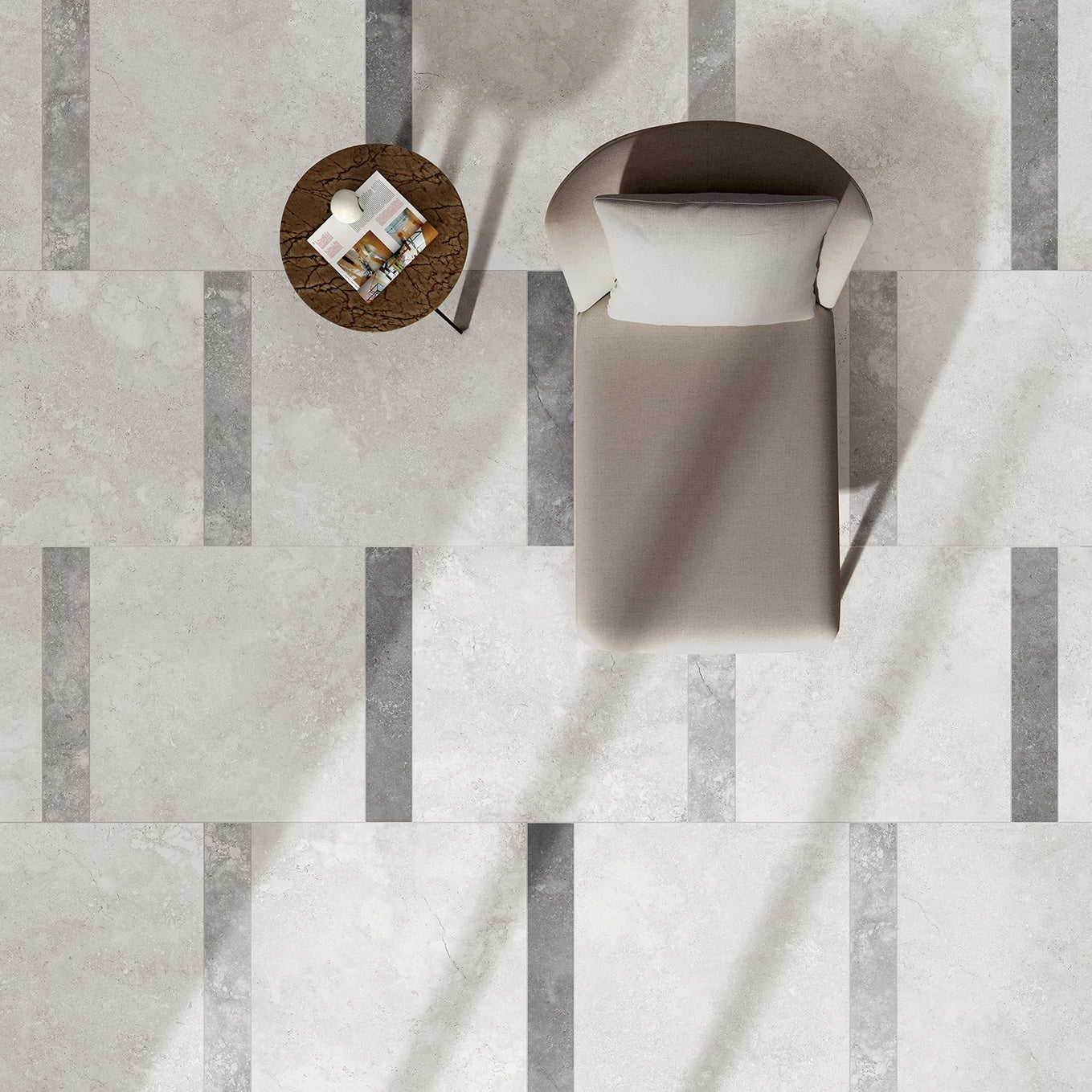 Dino Bianco Rectified InOut 600x600mm light grey stone-effect floor tiles with darker grey stripe inlay detail, styled with a cream lounge chair and round marble side table, viewed from above.