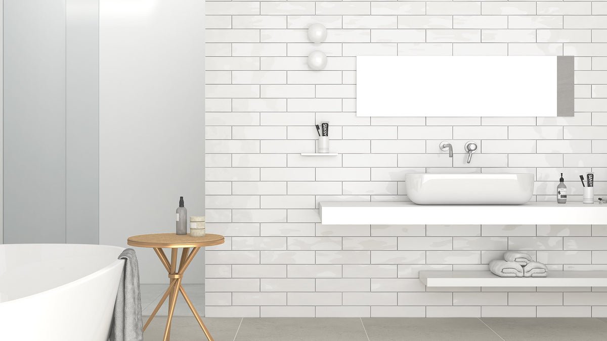Edge White Wave Gloss 68x280mm subway tiles installed as a full bathroom feature wall behind a floating white vanity with vessel sink and gold side table.