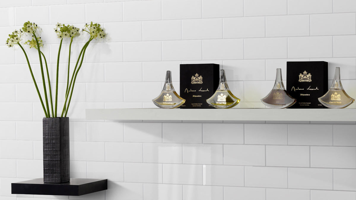 Edge White Wave Gloss 68x280mm white subway tiles installed as a wall backdrop with floating shelves displaying luxury perfume bottles and a black vase with flowers.