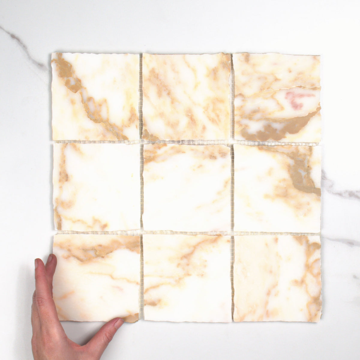 Elementa Calacatta Gold Mosaic 100x100mm top view, hand for scale