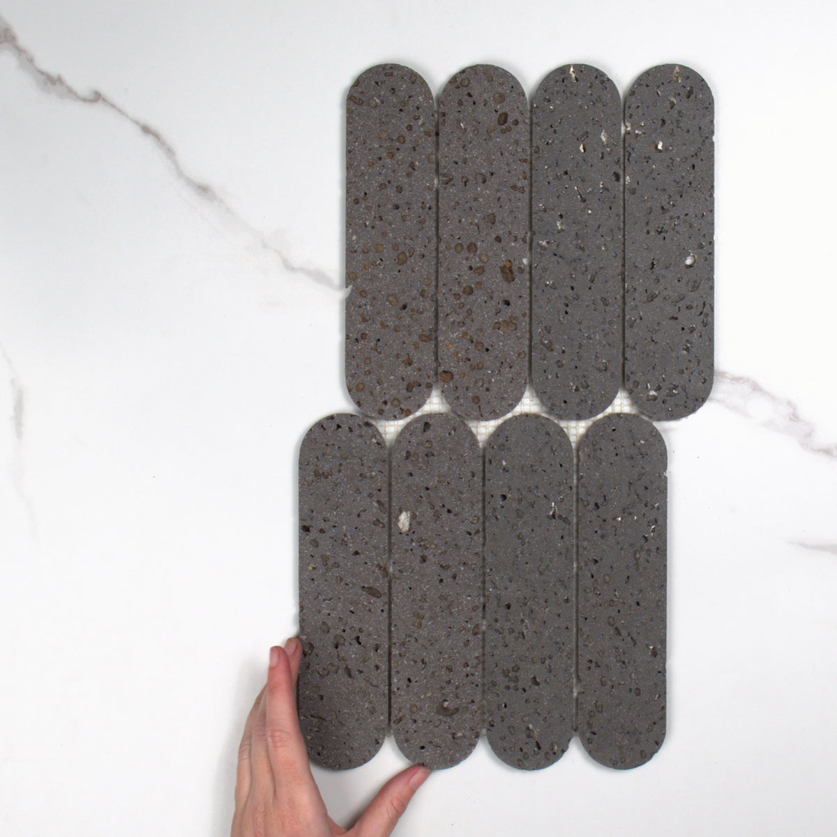 Elementa Travertine Black Cylinder Mosaic 50x198mm top view, hand for scale
