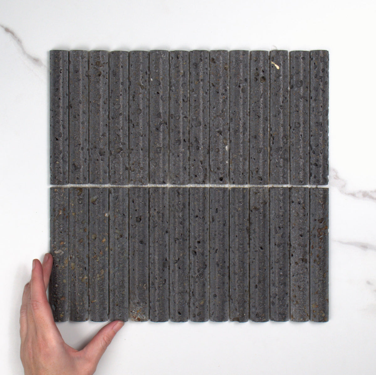 Elementa Travertine Black Fluted Mosaic 20x148mm top view, hand for scale