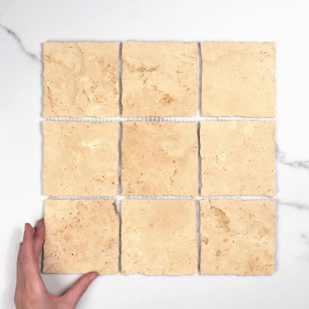 Elementa Travertine Ivory Mosaic 100x100mm top view, hand for scale