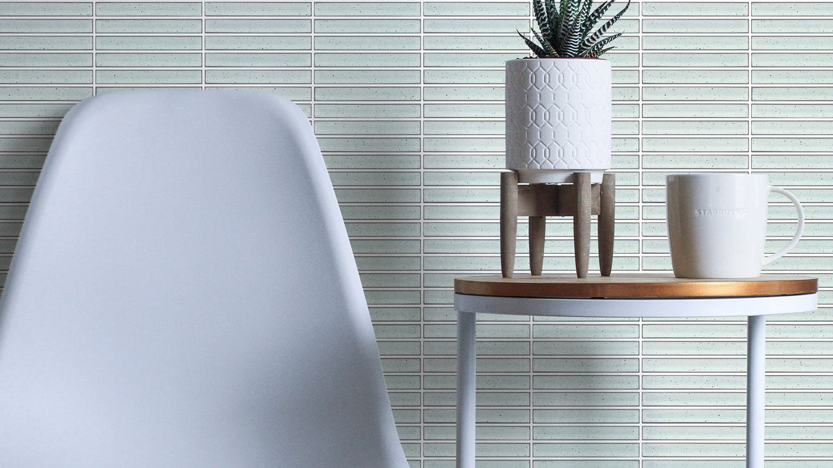 Finger Speckle Mosaic White Gloss 20x145mm tiles covering a feature wall in a modern living space styled with a white chair and timber side table.