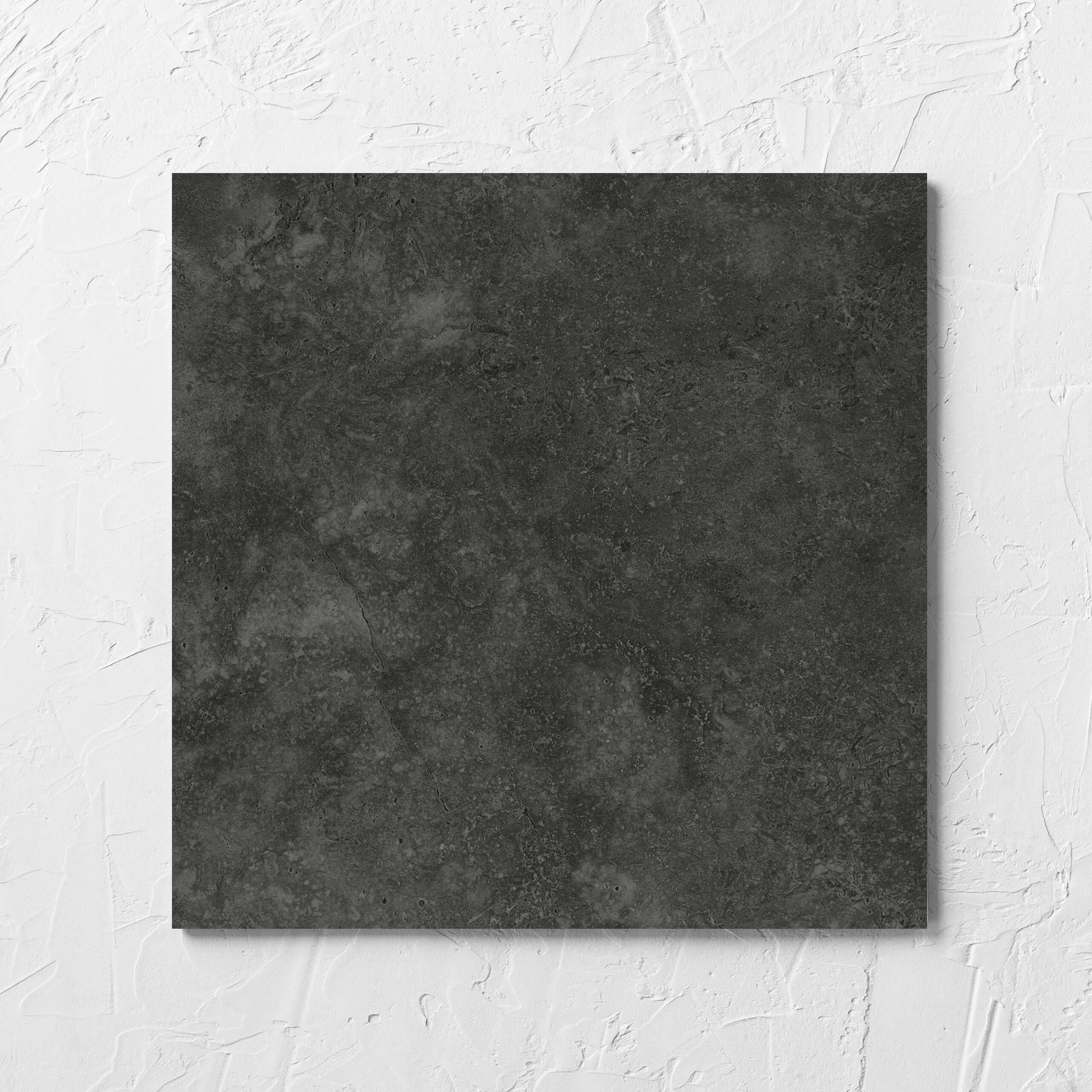 Fossil Stone Coal Matt 300x300mm tile laid flat on a white rendered wall, showing the matt surface