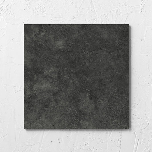 Fossil Stone Coal Matt 300x300mm tile laid flat on a white rendered wall, showing the matt surface
