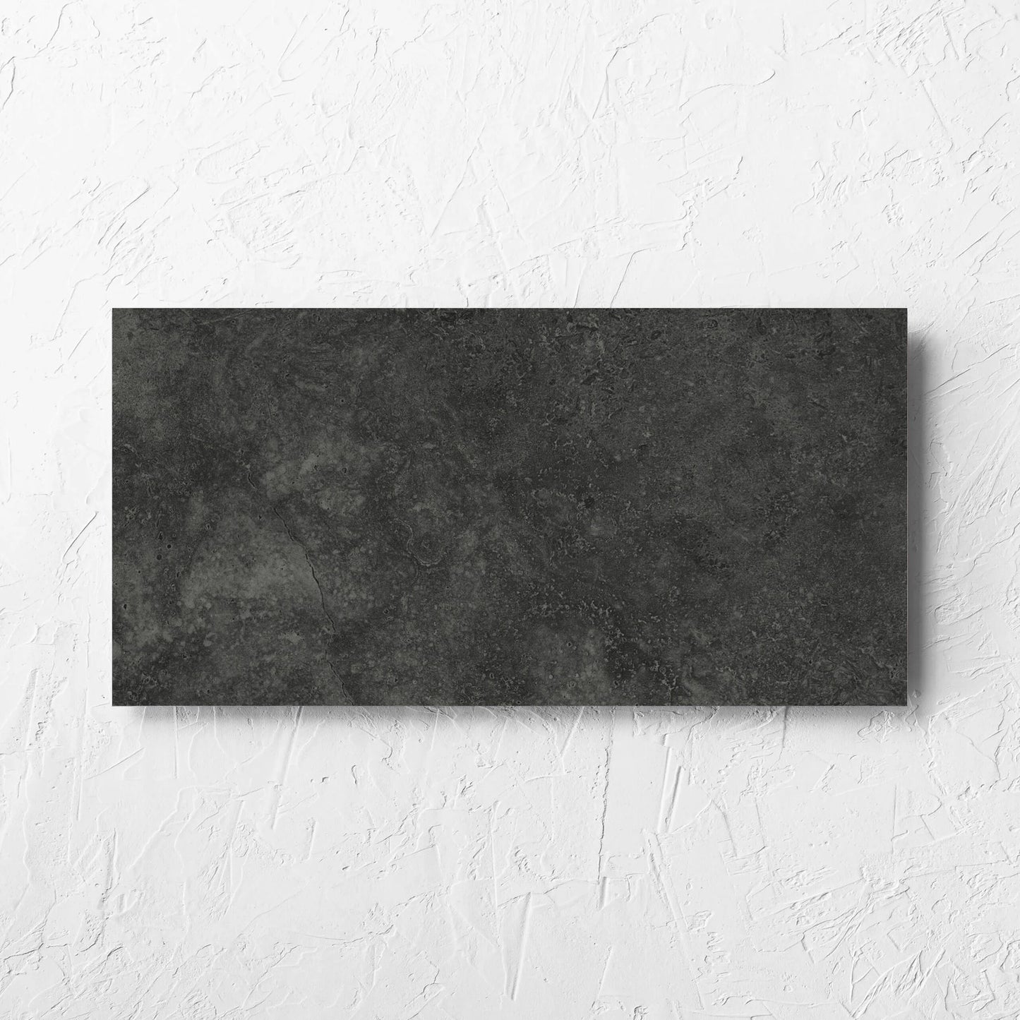 Fossil Stone Coal Matt 300x600mm tile laid flat on a white rendered wall, showing the matt surface
