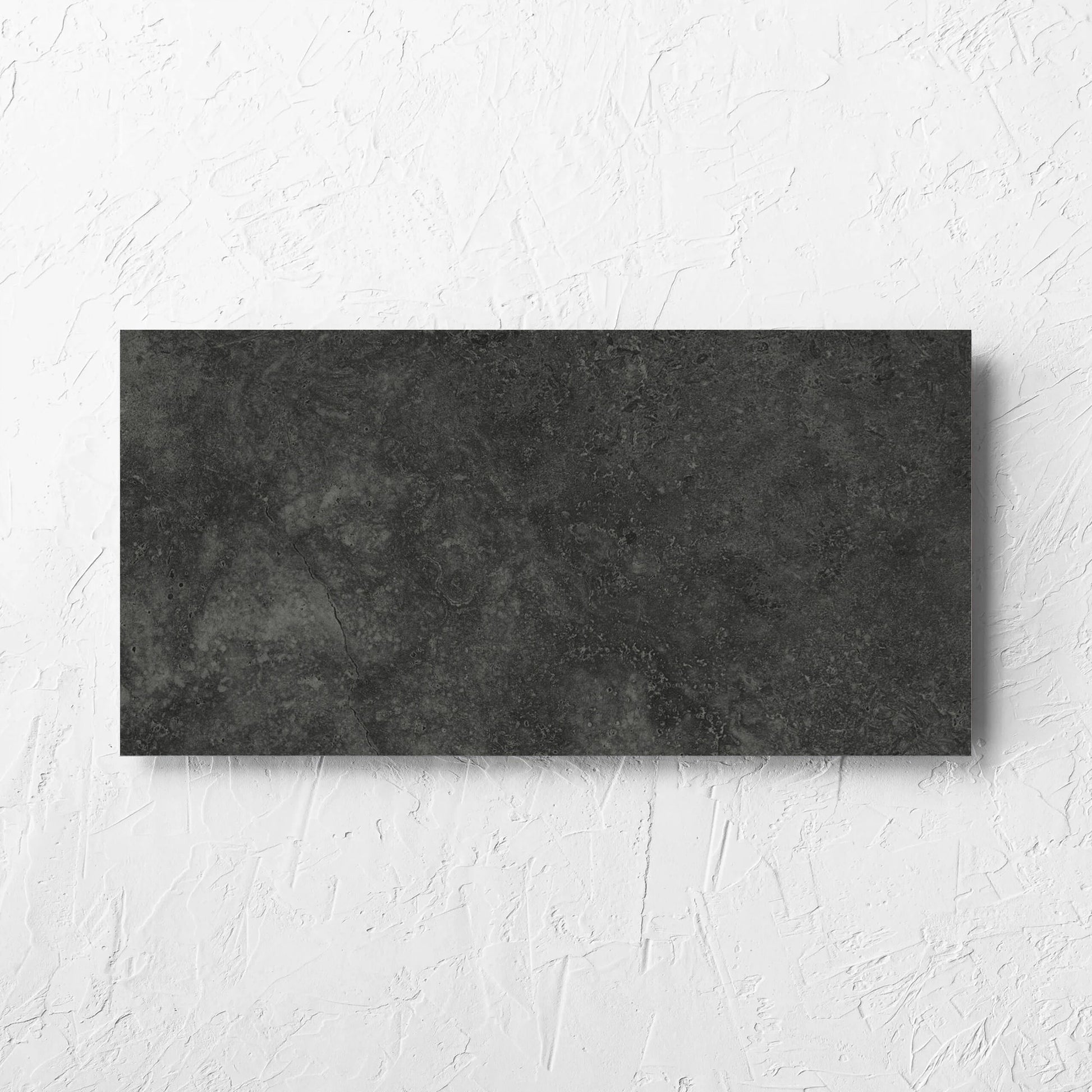 Fossil Stone Coal Matt 300x600mm tile laid flat on a white rendered wall, showing the matt surface