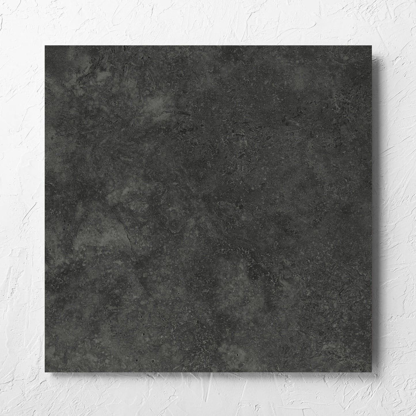 Fossil Stone Coal Matt 600x600mm tile laid flat on a white rendered wall, showing the matt surface