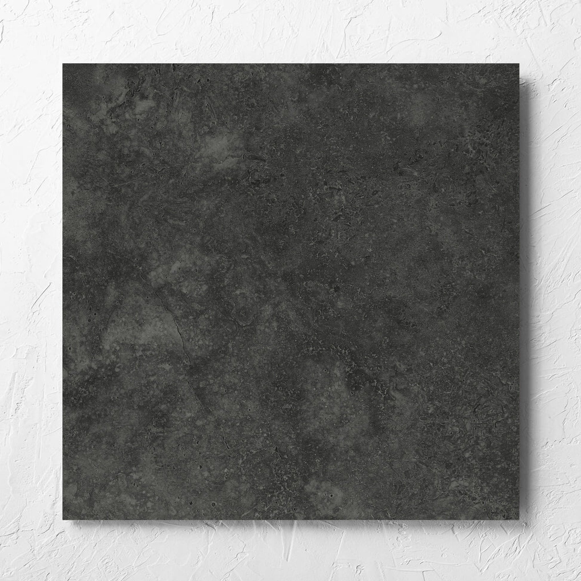 Fossil Stone Coal Matt 600x600mm tile laid flat on a white rendered wall, showing the matt surface