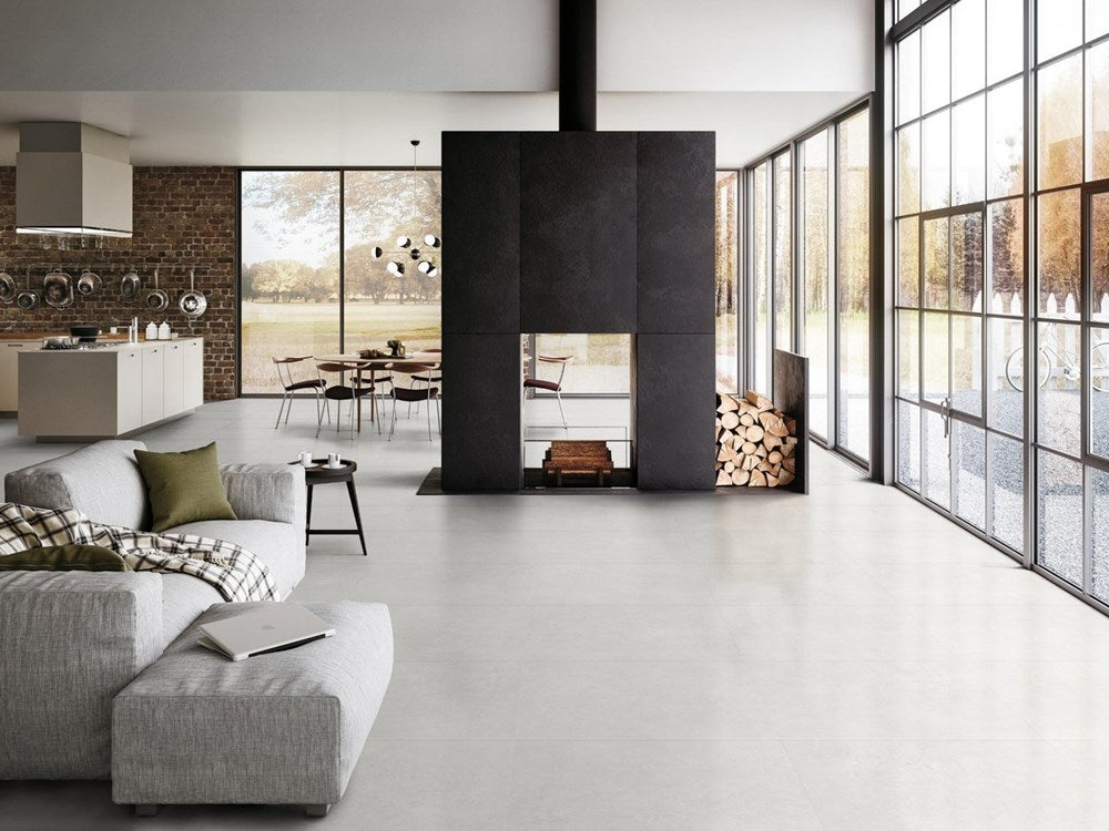 Fossil Stone Pebble Matt 300x300mm tiles laid across a bright open-plan living room floor featuring a modern black fireplace and floor-to-ceiling windows.