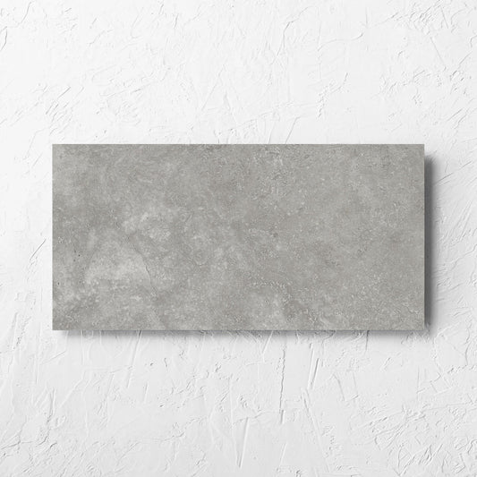 Fossil Stone Pebble Matt 300x600mm tile laid flat on a white rendered wall, showing the matt surface