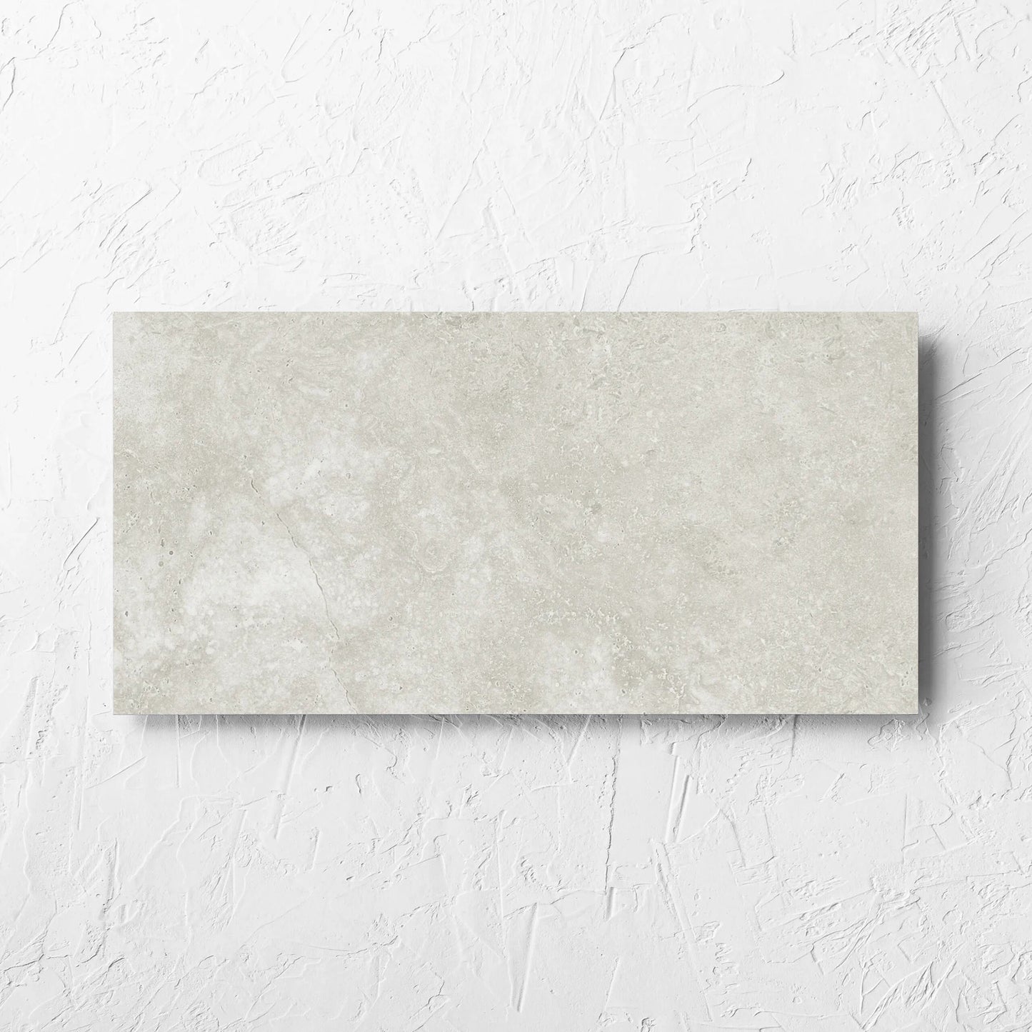 Fossil Stone Sand Matt 300x600mm tile laid flat on a white rendered wall, showing the matt surface