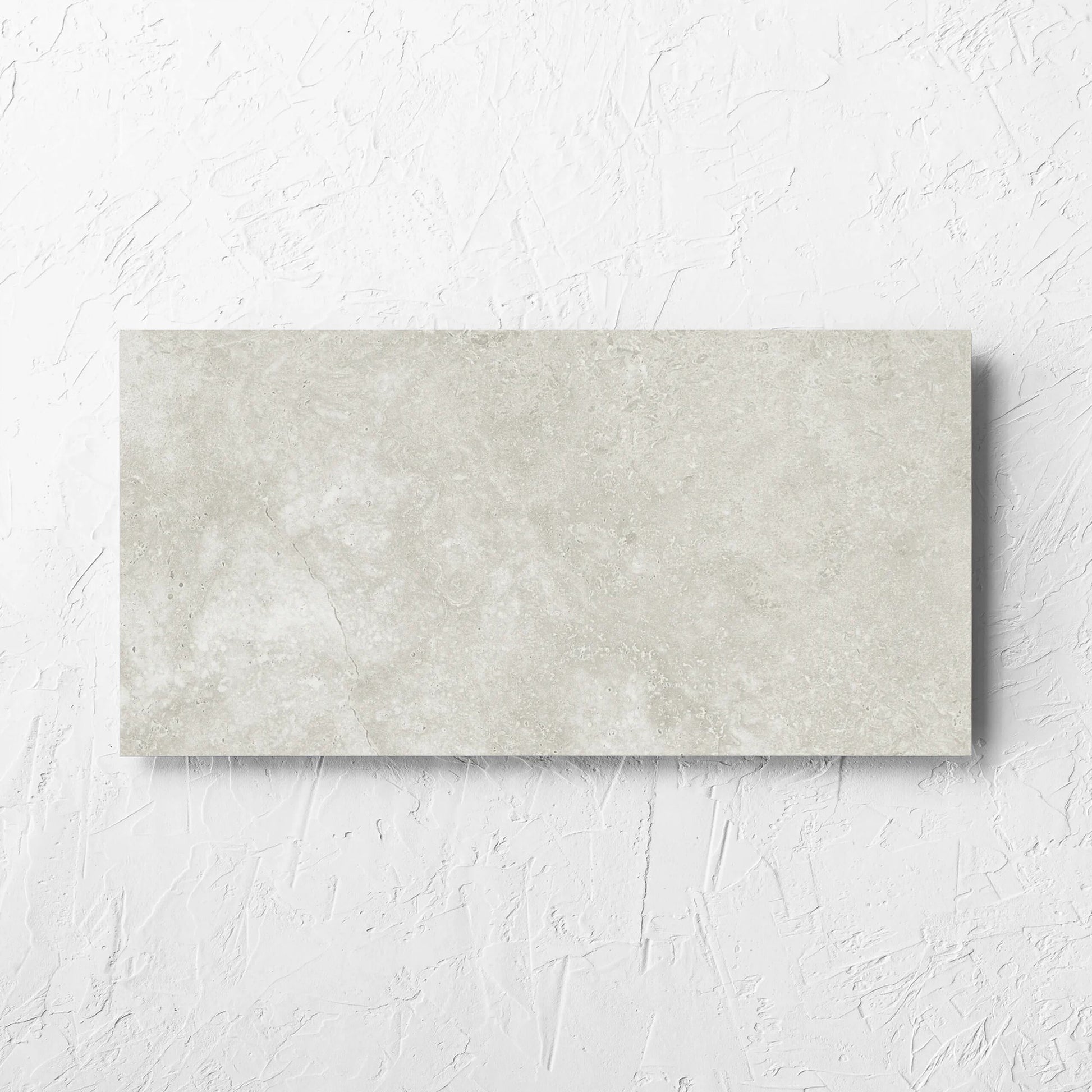 Fossil Stone Sand Matt 300x600mm tile laid flat on a white rendered wall, showing the matt surface