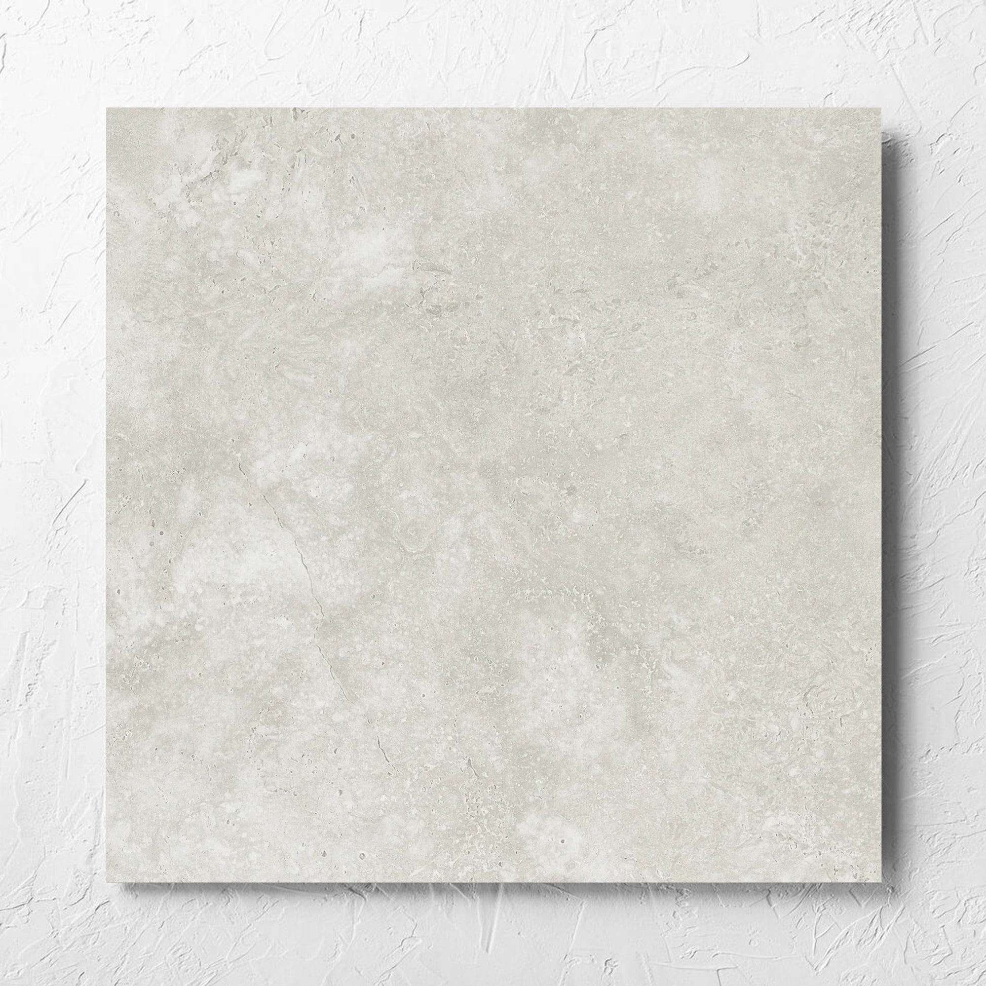 Fossil Stone Sand Matt 600x600mm tile laid flat on a white rendered wall, showing the matt surface