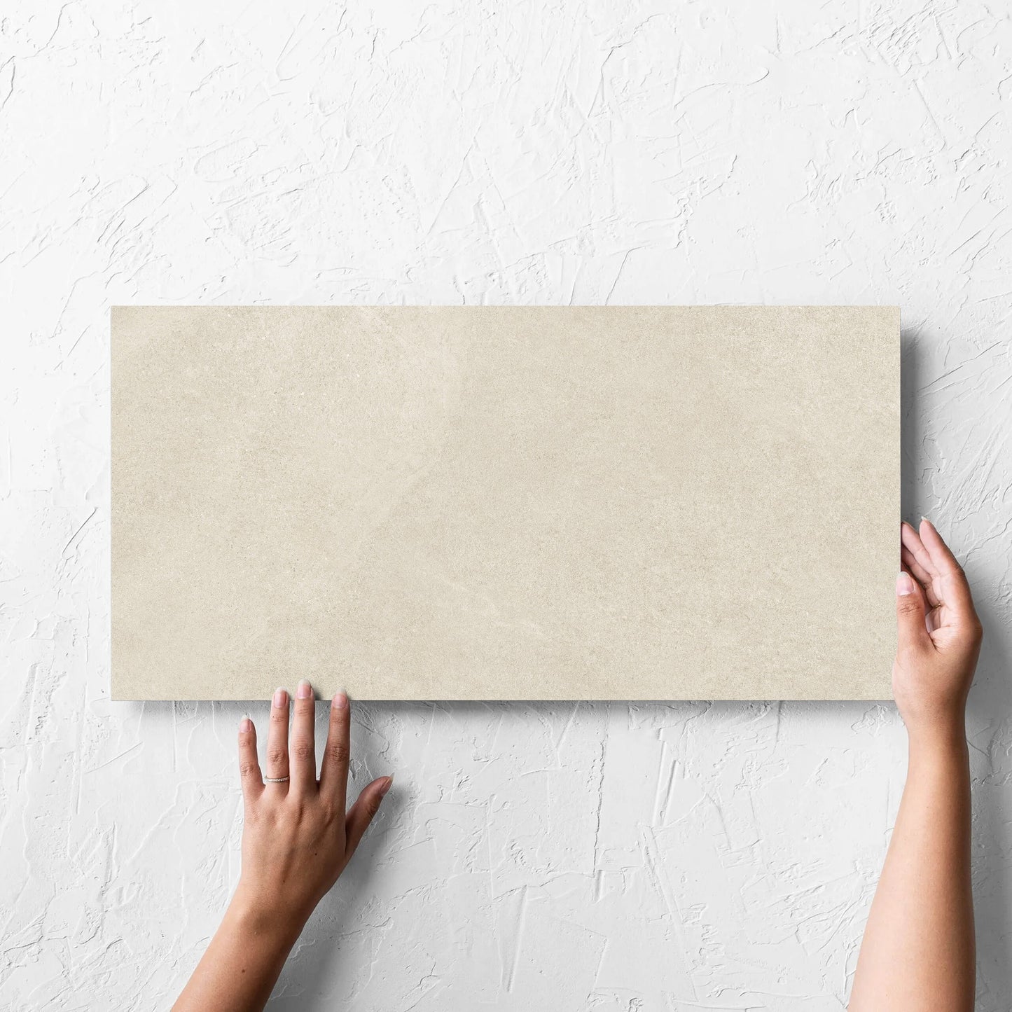 Hand holding a single Fusion Beige Ultra Tech 300x600mm tile against a white rendered wall, showing the matt surface