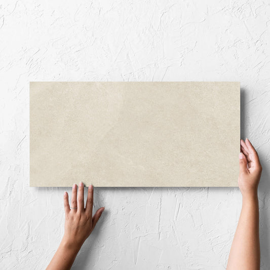Hand holding a single Fusion Beige Ultra Tech 300x600mm tile against a white rendered wall, showing the matt surface