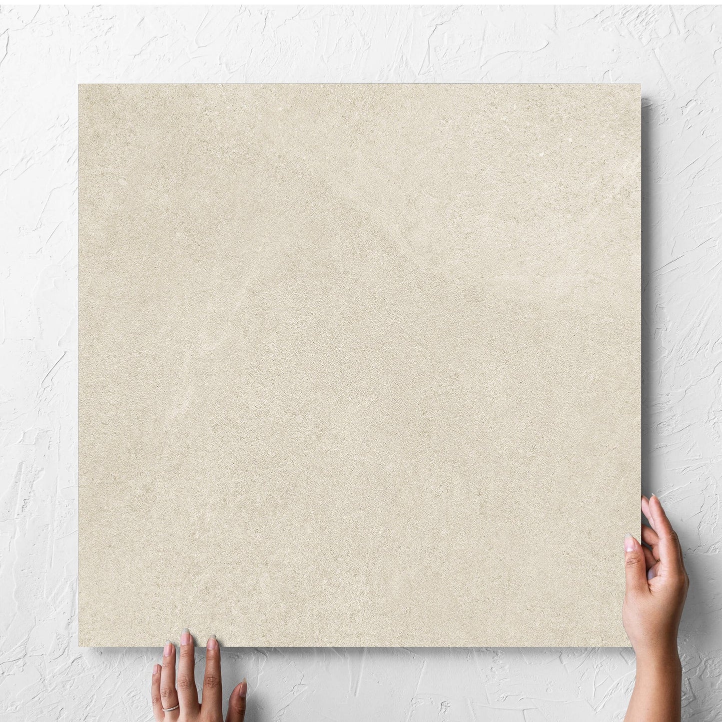 Hand holding a single Fusion Beige Ultra Tech 600x600mm tile against a white rendered wall, showing the matt surface