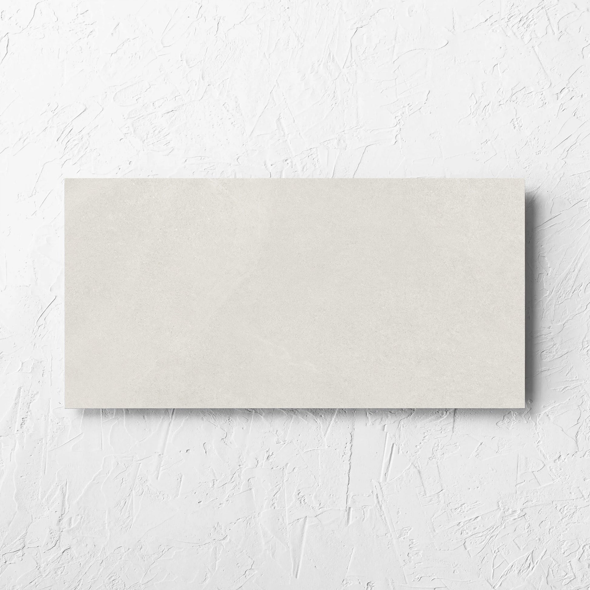 Fusion Bianco Ultra Tech 300x600mm tile laid flat on a white rendered wall, showing the matt surface