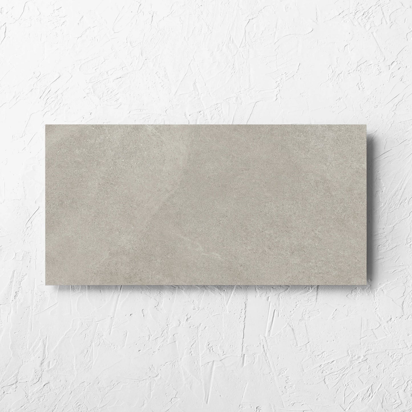 Fusion Cenere Ultra Tech 300x600mm tile laid flat on a white rendered wall, showing the matt surface