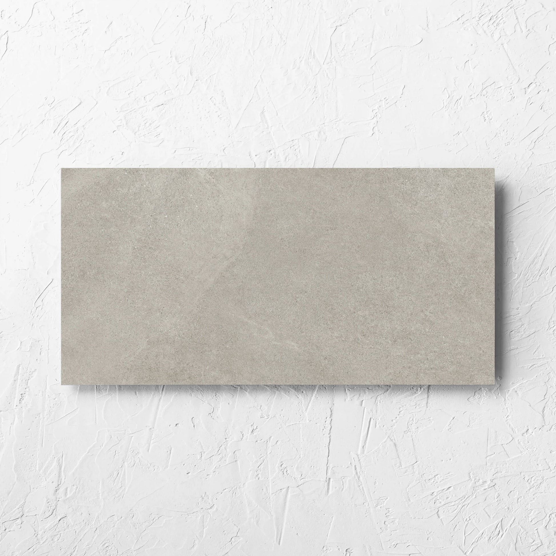 Fusion Cenere Ultra Tech 300x600mm tile laid flat on a white rendered wall, showing the matt surface