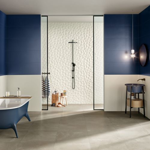 Genesis Leaf White 350x1000mm tiles installed as a textured shower feature wall in a modern bathroom with freestanding blue bathtub and pendant lighting.
