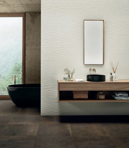 Genesis Reef White Matt Rectified 300x600mm tiles installed as a textured wave-pattern feature wall behind a timber vanity with black vessel sink and freestanding bath.
