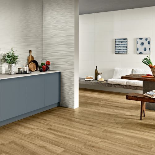 Genesis Wind White 350x1000mm wall tiles installed in an open-plan kitchen and living area featuring blue cabinetry and wood-effect flooring.