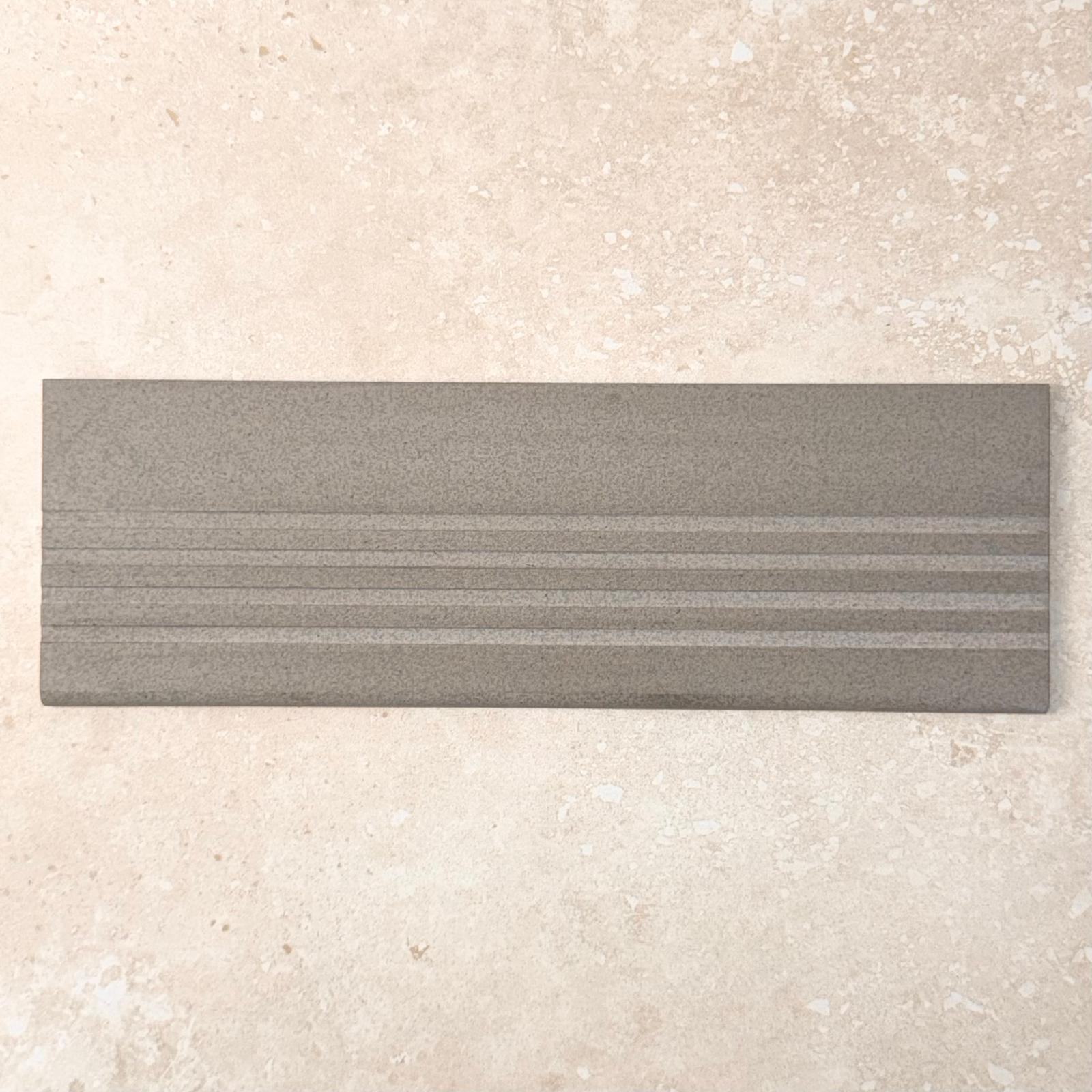 Grey Step Tread 60x300mm tile shown as a pack shot, featuring a matte grey finish with three raised parallel ribbed lines for slip resistance.