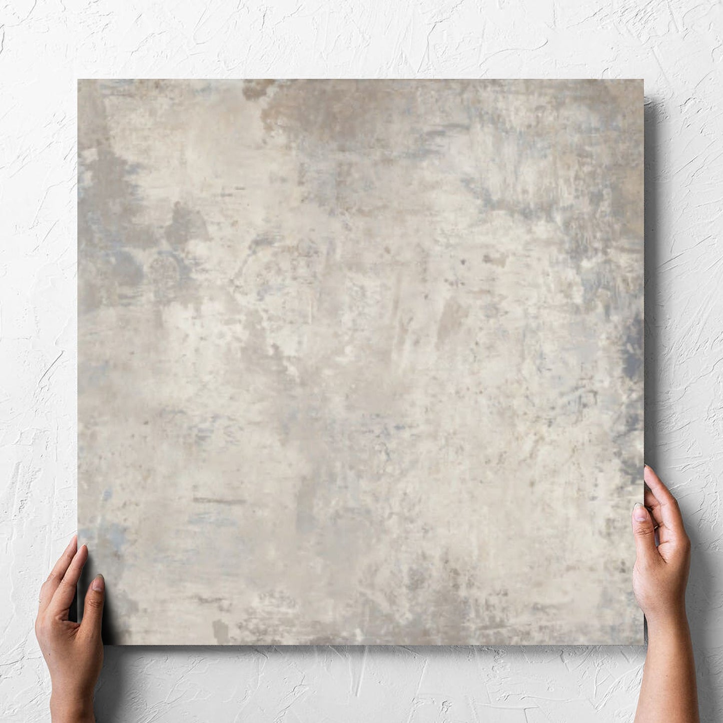 Hand holding a single Grunge Beige Rectified 600x600mm tile against a white rendered wall, showing the tile surface