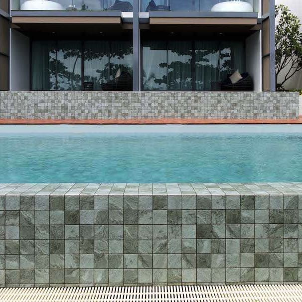 Hammond Green Mosaic 97x97mm tiles installed on a modern infinity pool surround and coping wall, showcasing their green marble-look finish against clear blue water and a contemporary villa facade.