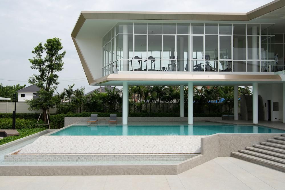 Hammond Light Grey Mosaic 97x97mm tiles installed around a modern outdoor swimming pool deck and wading area beside a contemporary glass-facade clubhouse.