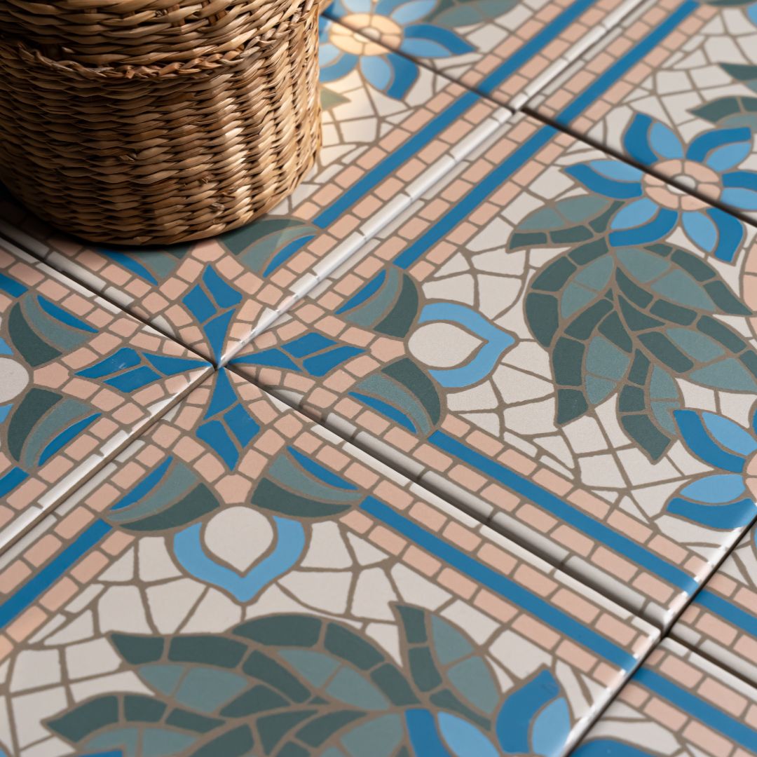 Highbury Ariadna 147x147mm decorative floor tiles in blue, sage green, and blush featuring a botanical mosaic pattern, styled with a wicker basket.