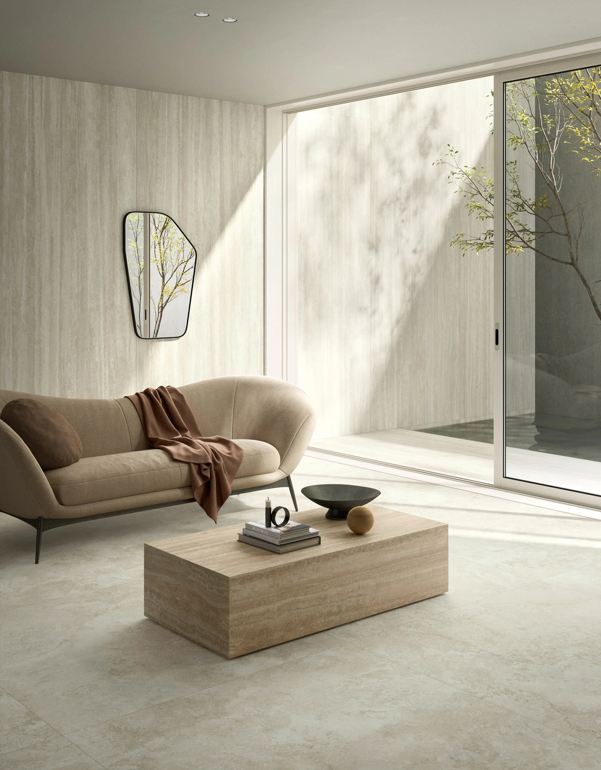 Ic.Verso Classico Gr 600x1200mm light stone-look floor tiles in a minimalist living room with a beige sofa, travertine coffee table, and floor-to-ceiling sliding glass doors.
