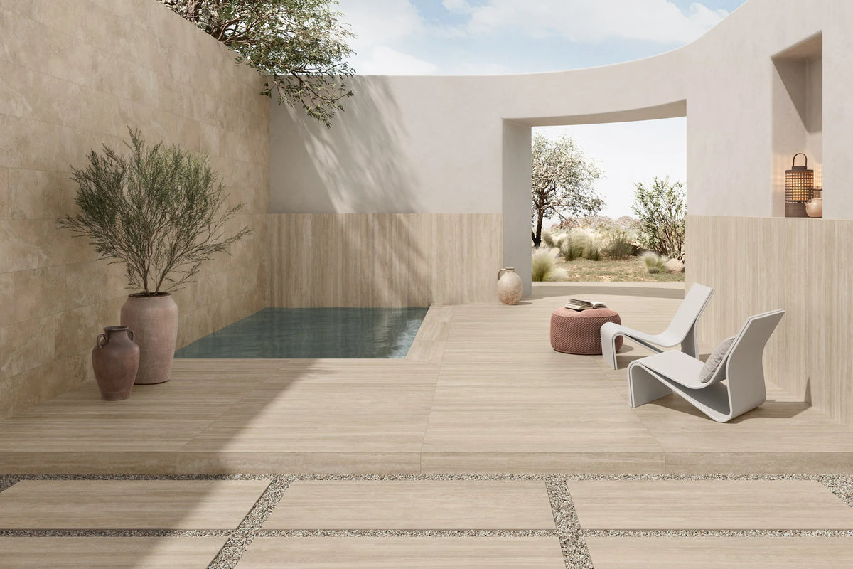 Ic.Verso Classico Gr 600x1200mm porcelain tiles in warm beige travertine finish laid on a sunlit Mediterranean-style outdoor terrace with plunge pool and lounge chair.
