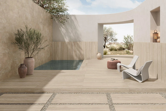 Ic.Verso Classico Gr 600x1200mm porcelain tiles in warm beige travertine finish laid on a sunlit Mediterranean-style outdoor terrace with plunge pool and lounge chair.