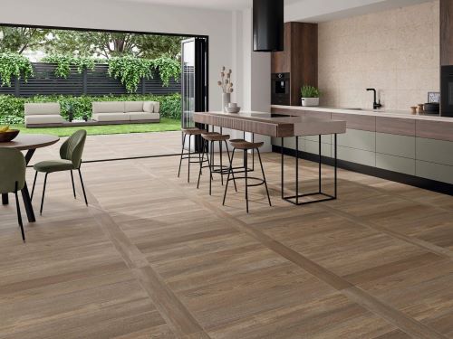Inout Olson Walnut 230x1200mm wood-look porcelain tiles installed across an open-plan kitchen and outdoor entertaining area with island bar stools.