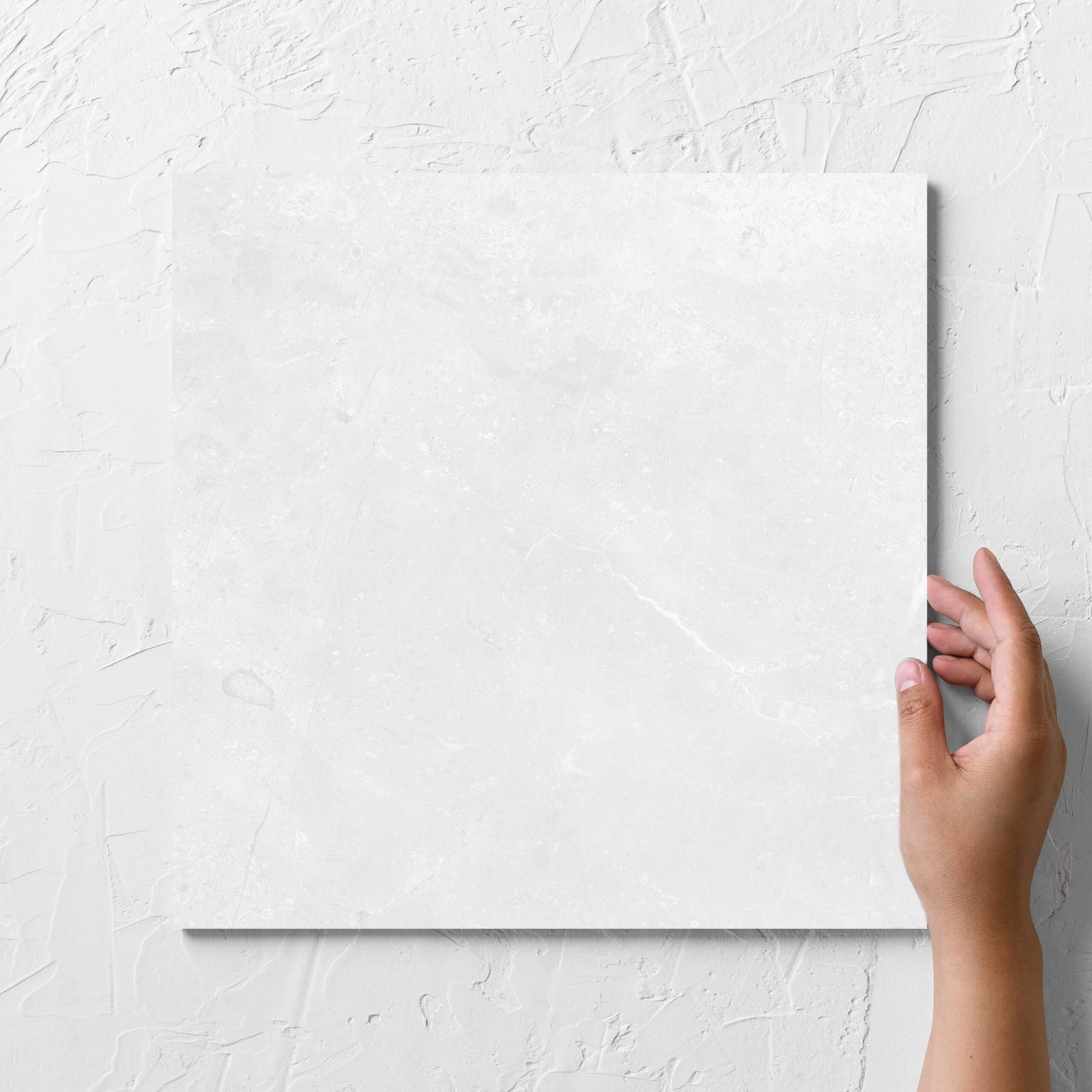 Hand holding a single Kashmir Bone Matt 300x300mm tile against a white rendered wall, showing the matt surface