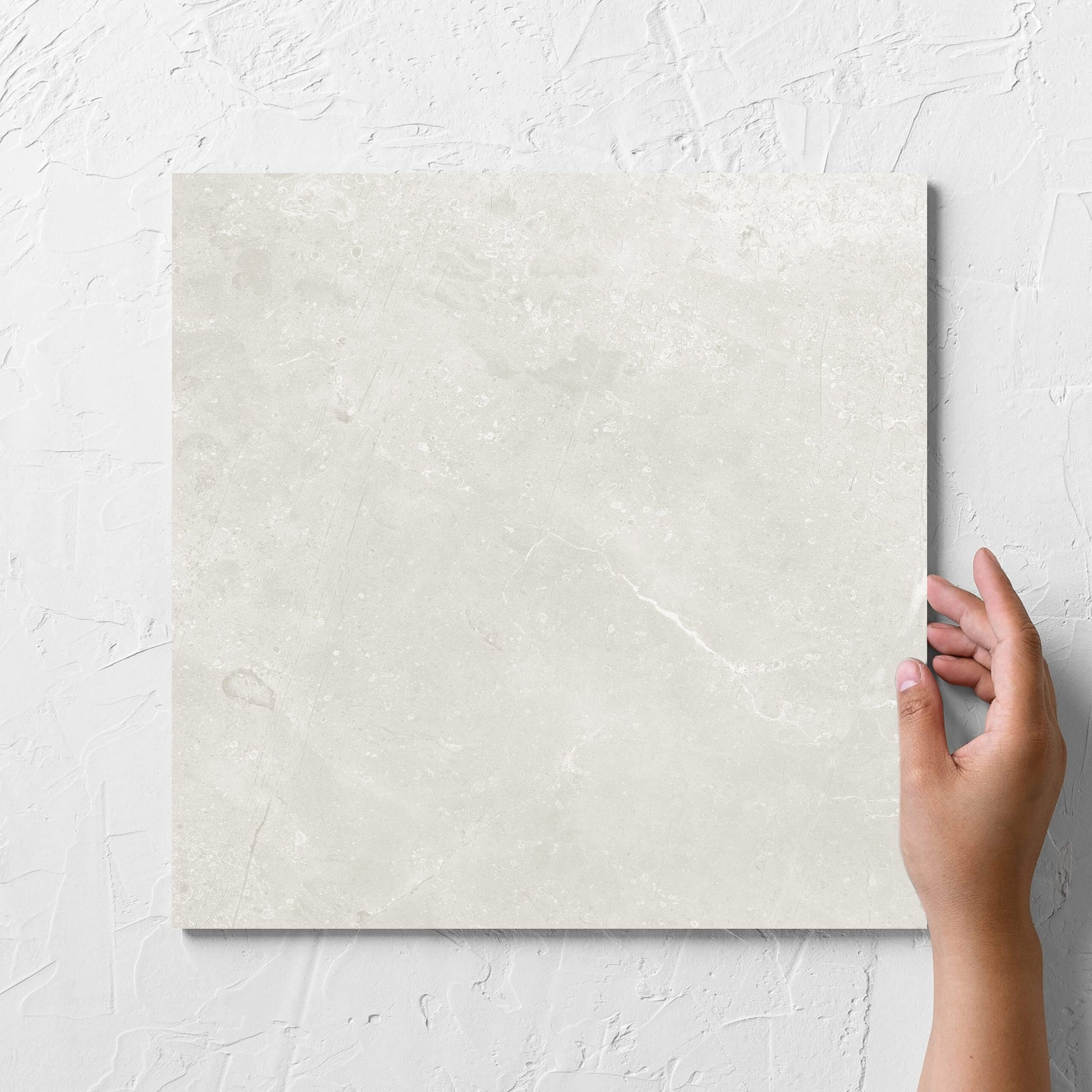 Hand holding a single Kashmir Natural Matt 300x300mm tile against a white rendered wall, showing the matt surface