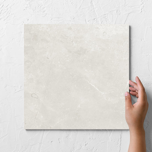 Hand holding a single Kashmir Natural Matt 300x300mm tile against a white rendered wall, showing the matt surface