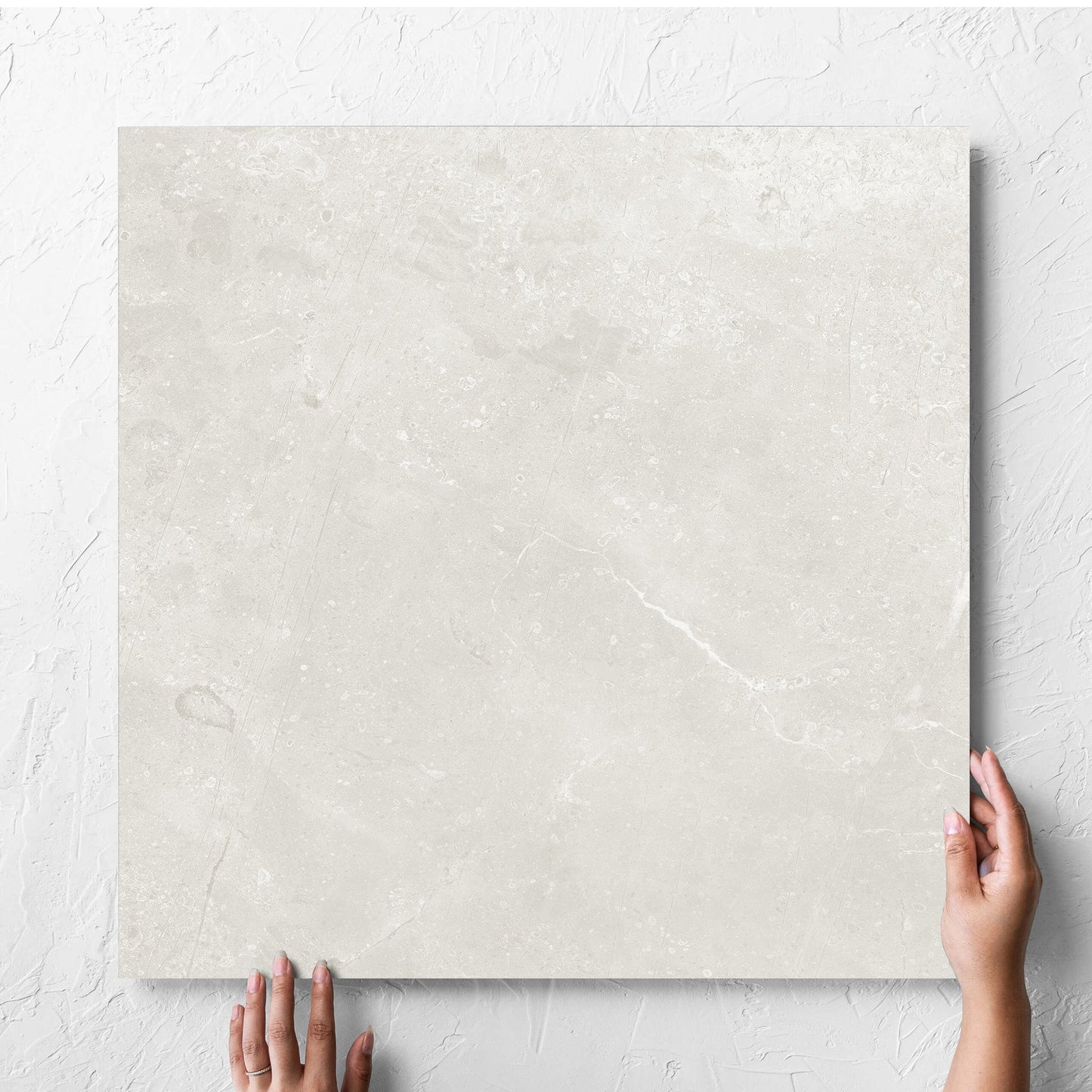 Hand holding a single Kashmir Natural Matt 600x600mm tile against a white rendered wall, showing the matt surface