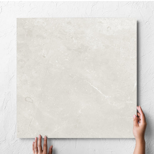 Hand holding a single Kashmir Natural Matt 600x600mm tile against a white rendered wall, showing the matt surface