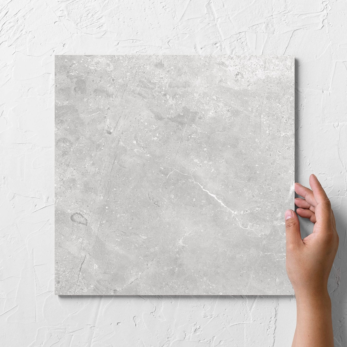 Hand holding a single Kashmir Stone Matt 300x300mm tile against a white rendered wall, showing the matt surface