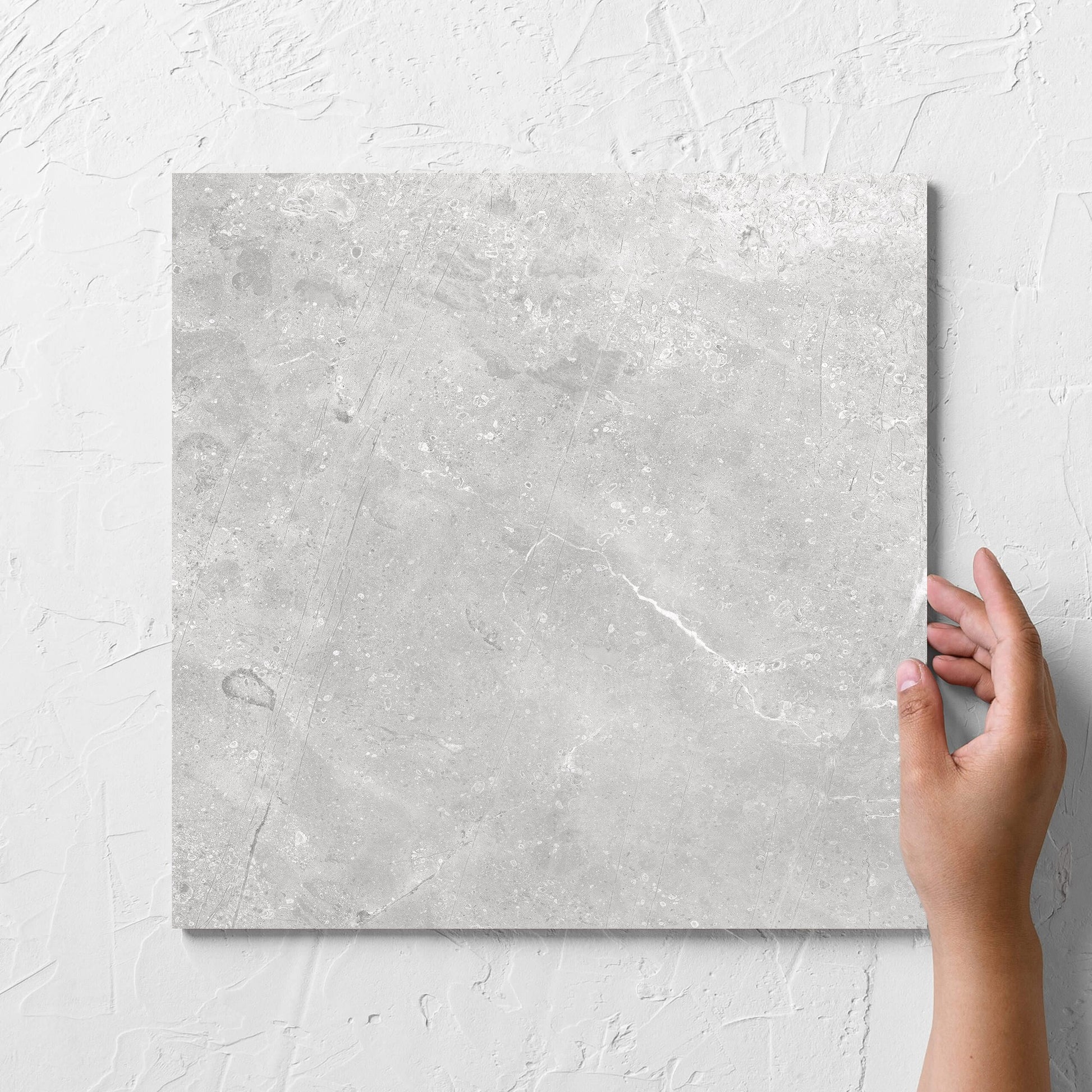 Hand holding a single Kashmir Stone Matt 300x300mm tile against a white rendered wall, showing the matt surface