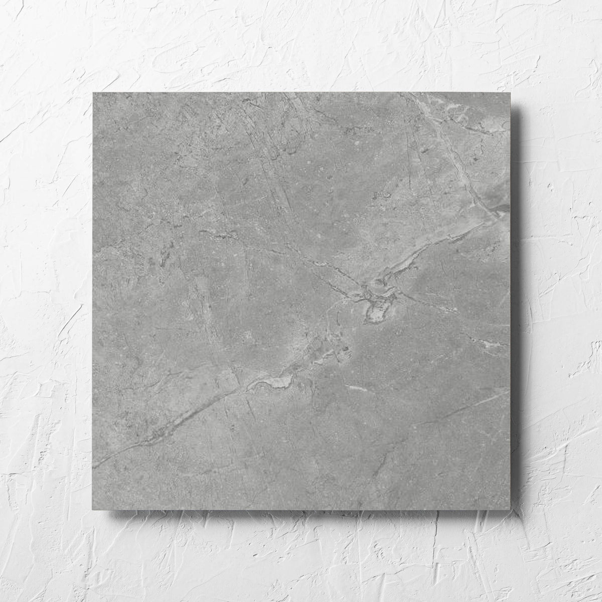 Kashmir Stone Matt 450x450mm tile laid flat on a white rendered wall, showing the grey matt surface