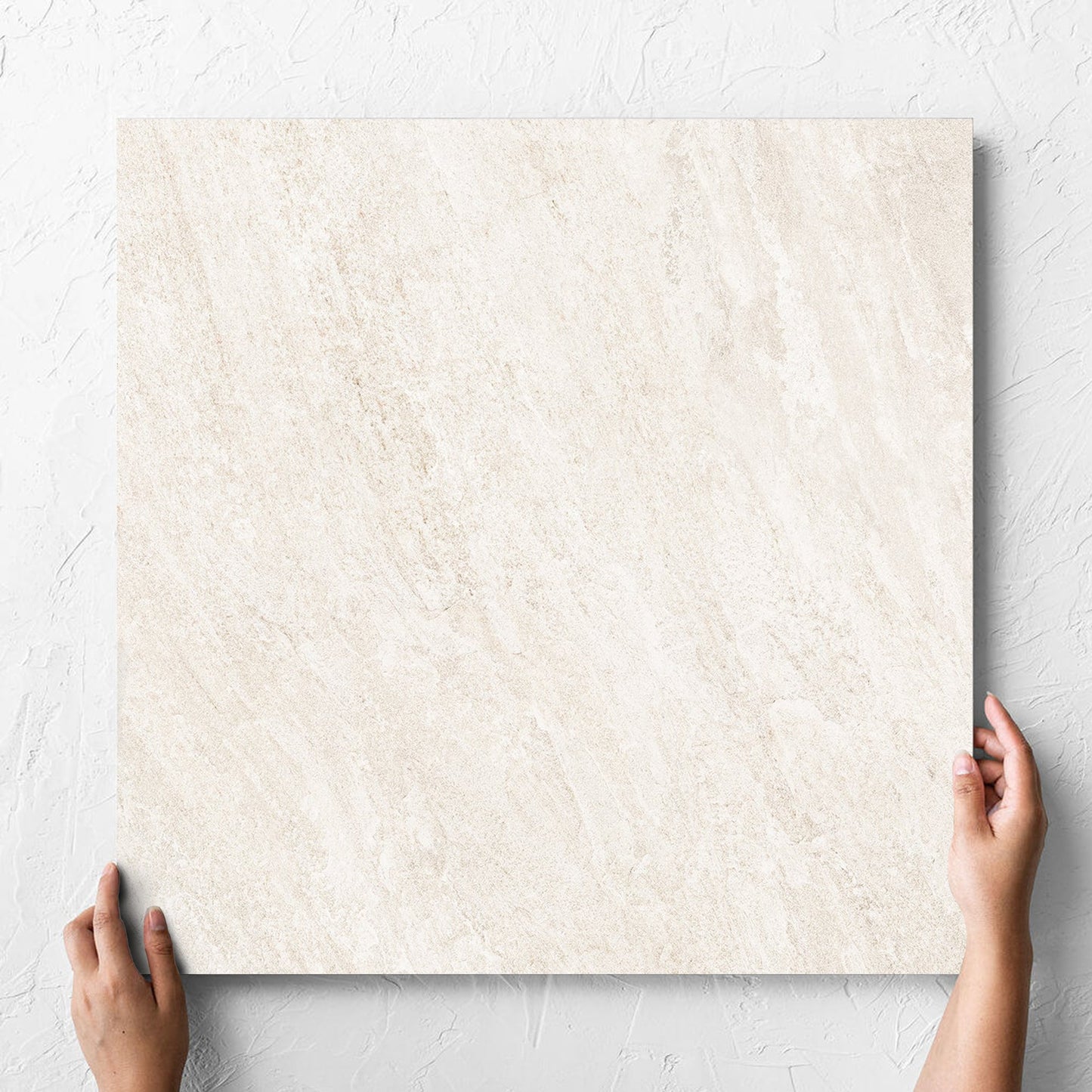 Hand holding a single Kora Stone Chalk Matt 600x600mm tile against a white rendered wall, showing the matt surface