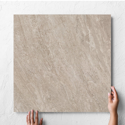 Hand holding a single Kora Stone Clay Grip 600x600mm tile against a white rendered wall, showing the matt surface