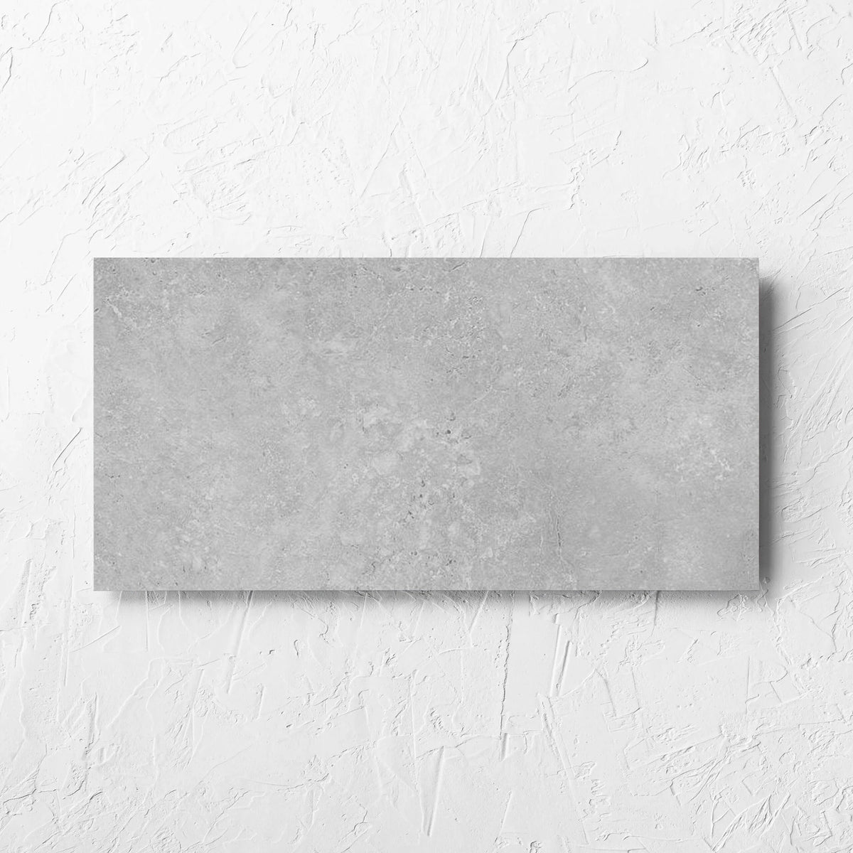 Kross Light Grey Matt Smooth Grip 300x600mm tile laid flat on a white rendered wall, showing the tile surface